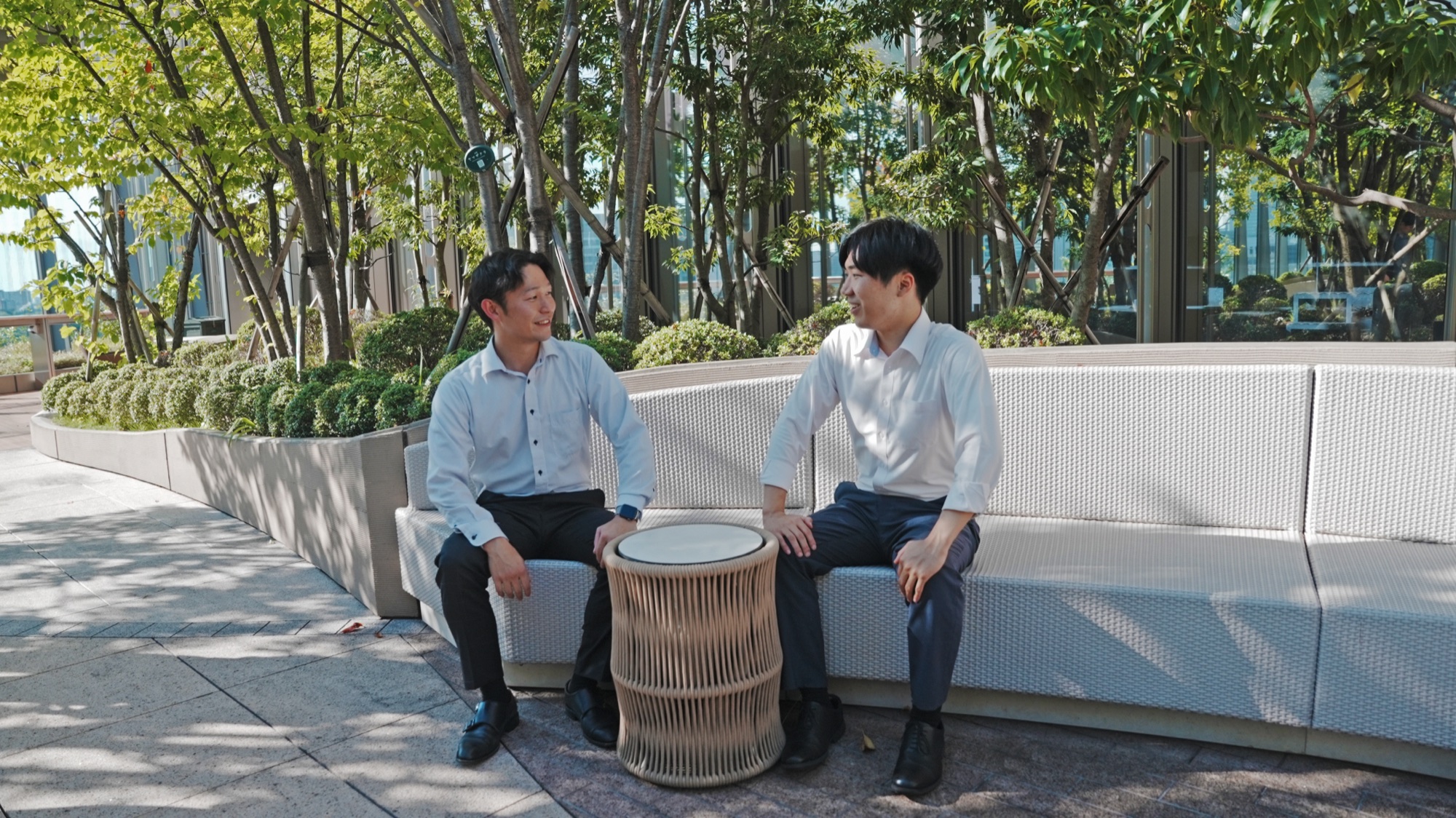 屋上庭園で先輩社員と話す 濱田