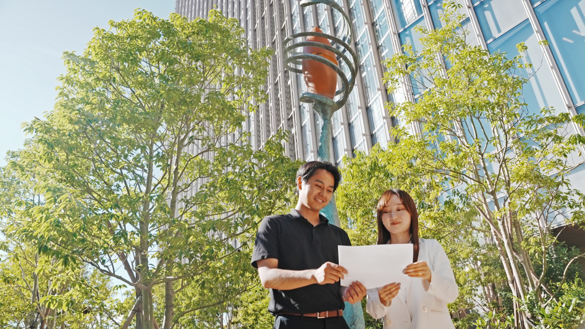 社屋前で資料を見ながら話す社員