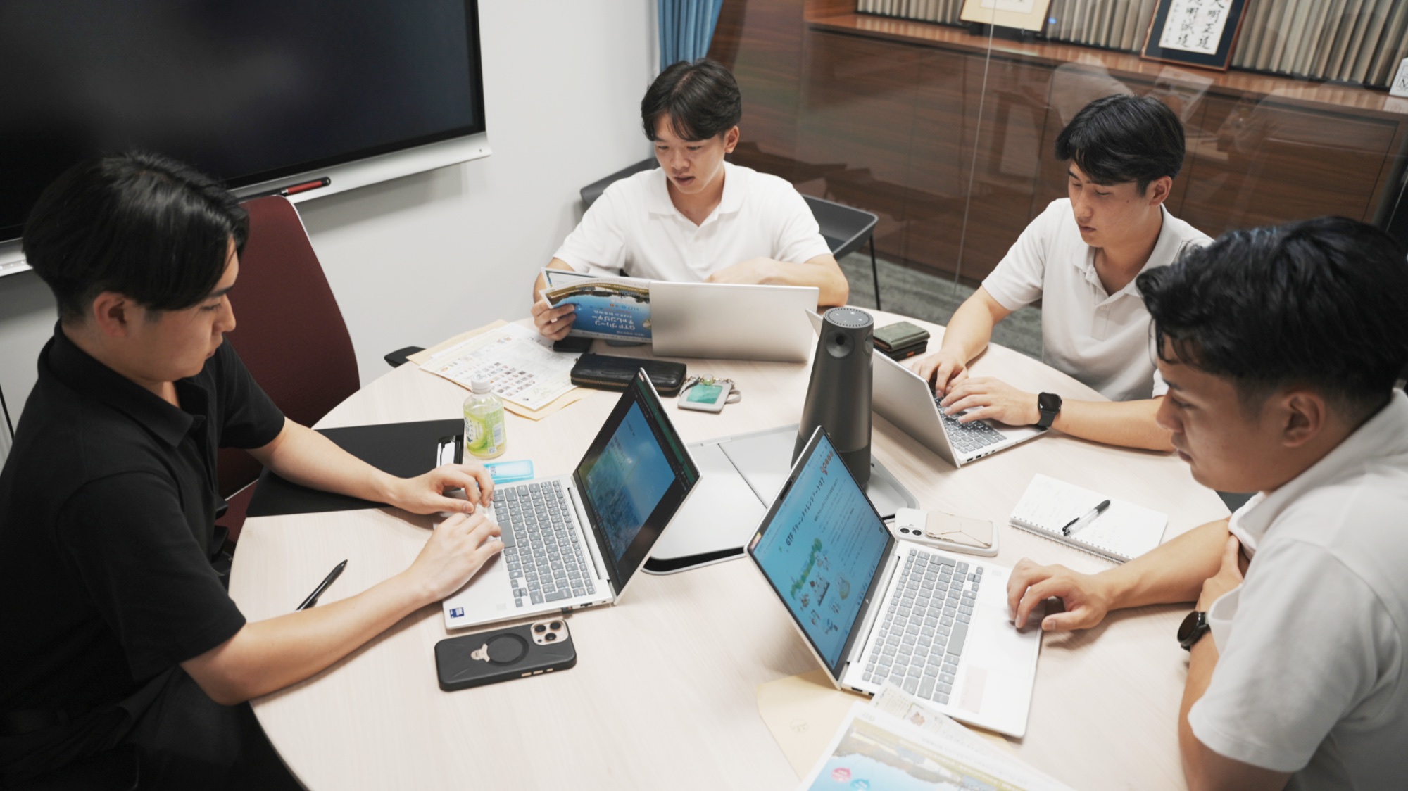 会議室で議論しながら作業する若手社員